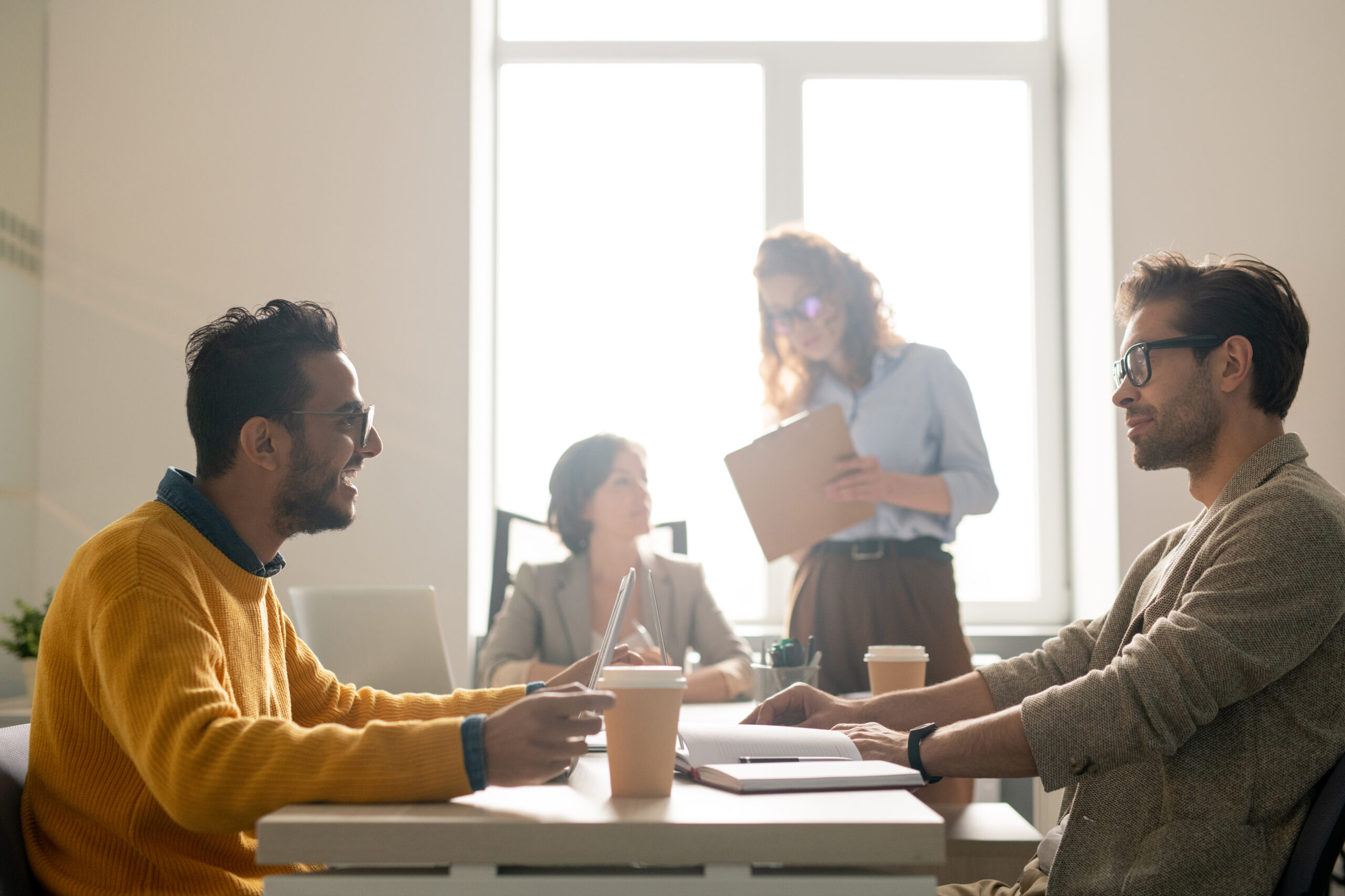 Positive young multi-ethnic marketing experts sitting at table