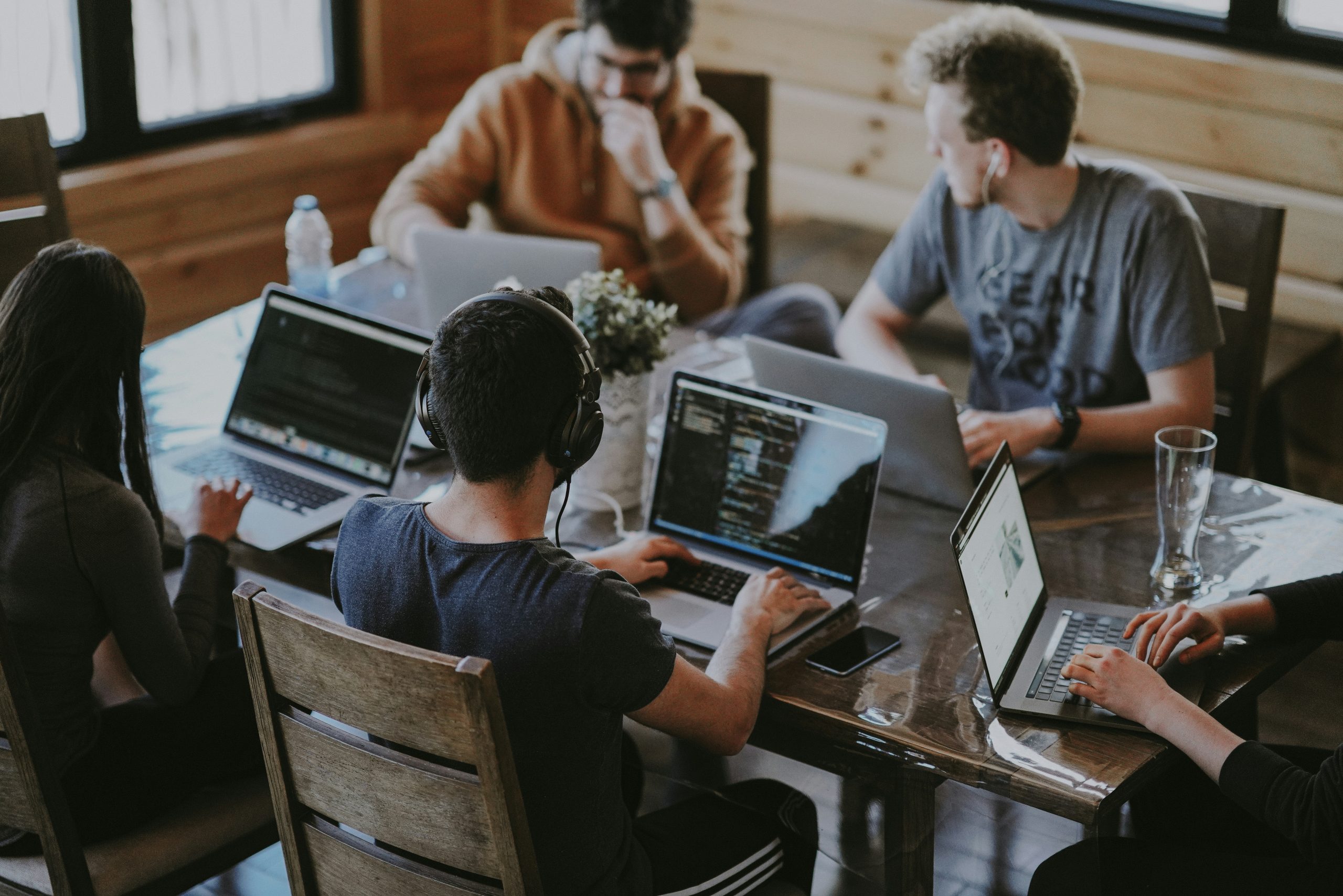 Team members working on laptops around a wooden table in a shared workspace